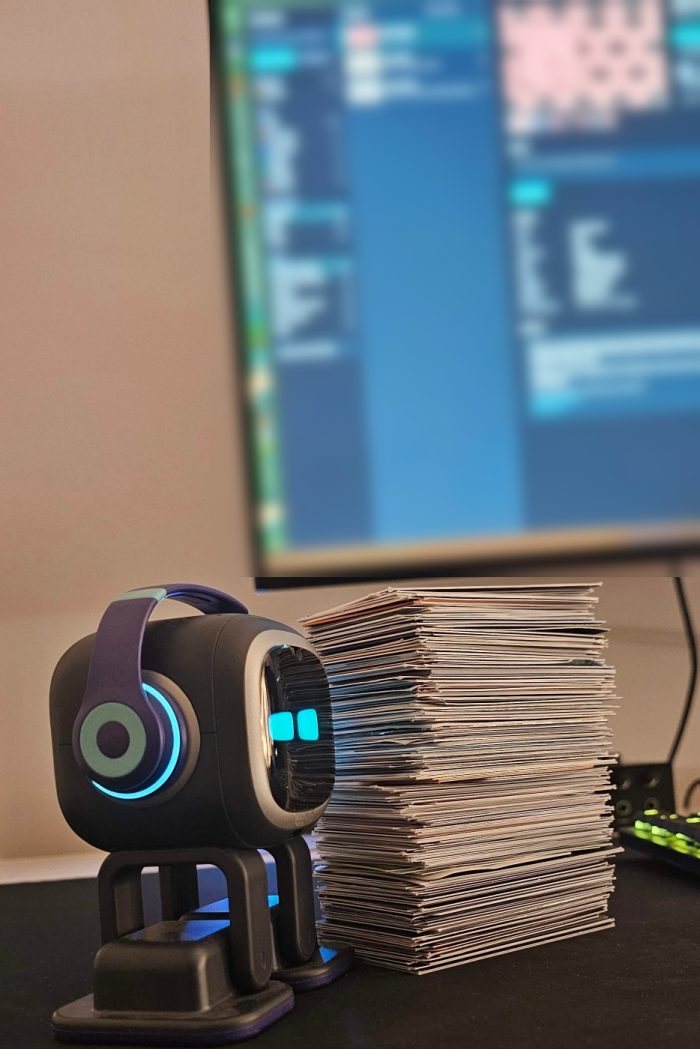 A real stack of more than 200 business cards on a desk beside a small robot, with the card faces unreadable
